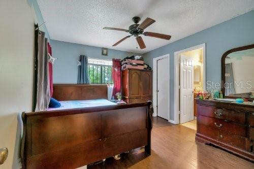 bedroom with ceiling fan, light hardwood / wood-style floors, and a textured ceiling