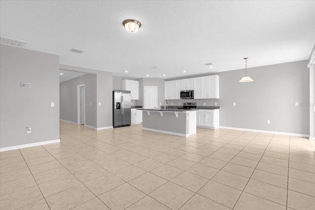 kitchen with open floor plan, white cabinets, stainless steel appliances, and visible vents