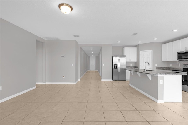 kitchen featuring a kitchen bar, a center island with sink, a sink, appliances with stainless steel finishes, and white cabinets