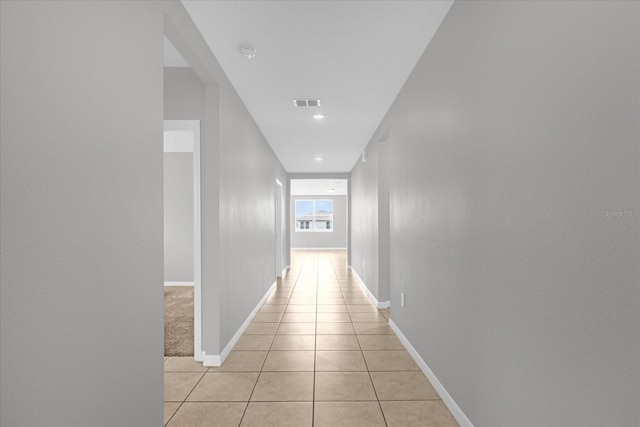 hall featuring light tile patterned flooring, baseboards, and visible vents