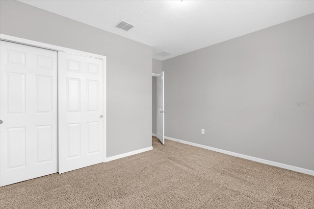 unfurnished bedroom with visible vents, baseboards, carpet, a closet, and a textured ceiling