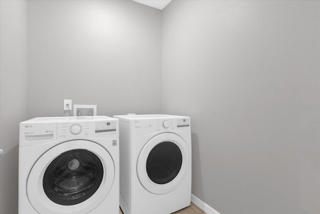 laundry area with light tile patterned flooring, laundry area, washer and dryer, and baseboards