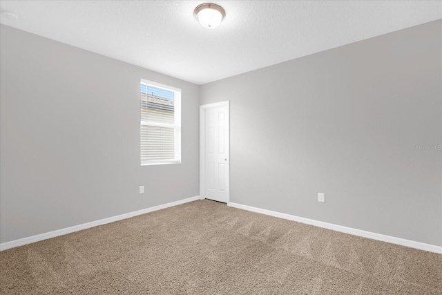 unfurnished room featuring baseboards and carpet