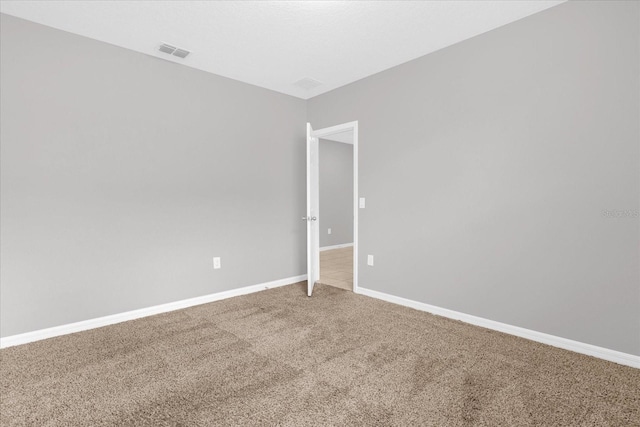 unfurnished room with visible vents, light colored carpet, and baseboards