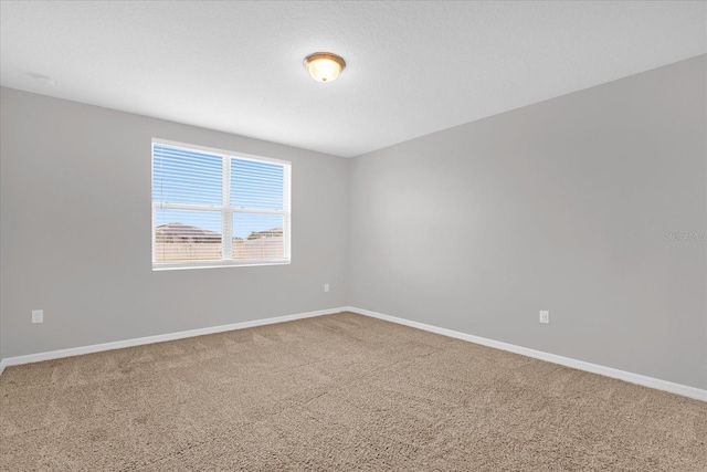 unfurnished room with carpet flooring and baseboards