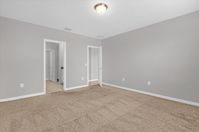 empty room with visible vents, light colored carpet, and baseboards