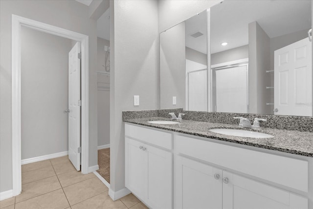 bathroom with tile patterned floors, double vanity, baseboards, and a sink