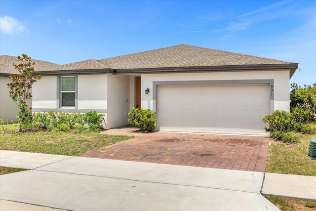 ranch-style home with a shingled roof, decorative driveway, a garage, and stucco siding