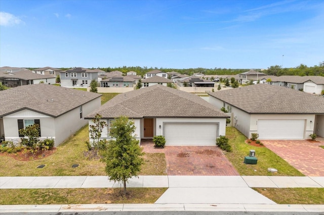 view of front of home with decorative driveway, a residential view, roof with shingles, and a front lawn