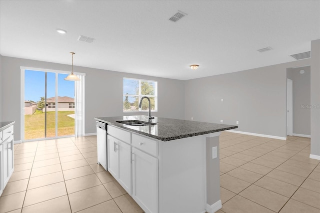 kitchen featuring dishwasher, dark stone counters, light tile patterned floors, white cabinets, and a sink