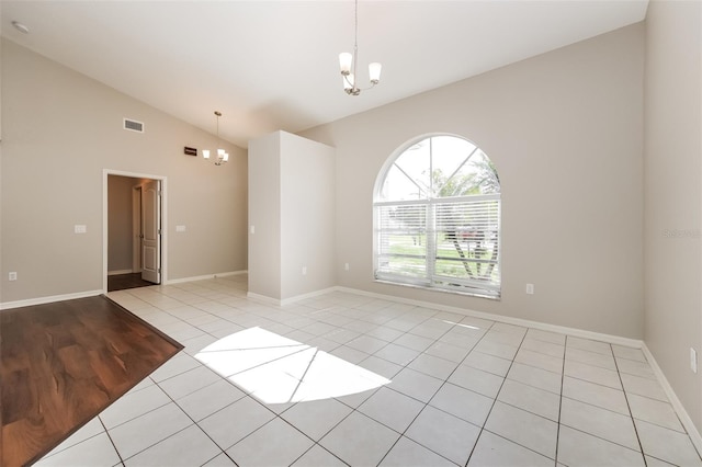 tiled empty room featuring a chandelier and lofted ceiling