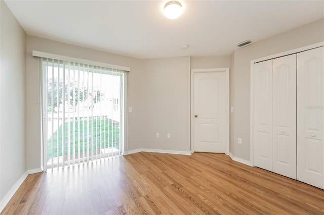 unfurnished bedroom featuring light hardwood / wood-style floors, access to exterior, and a closet