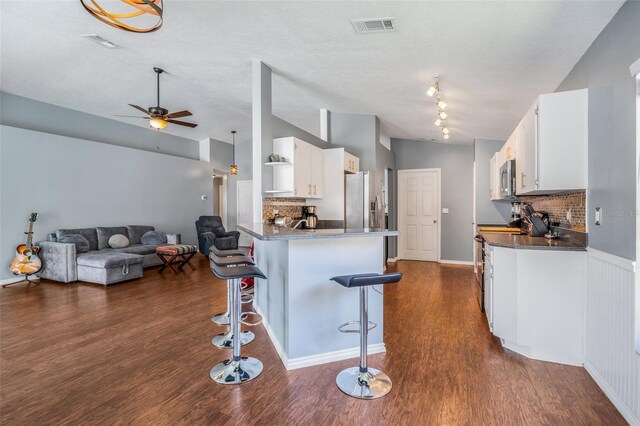 kitchen featuring a breakfast bar area, white cabinets, and backsplash