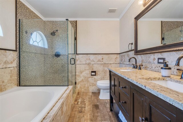 full bathroom with crown molding, double vanity, toilet, tile walls, and shower with separate bathtub