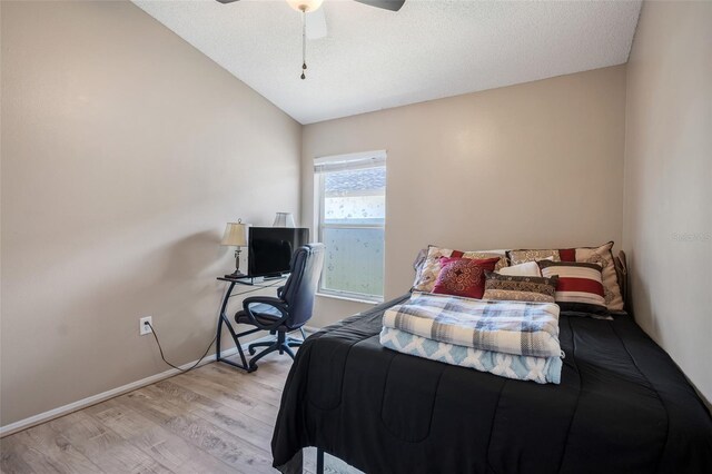 bedroom with a textured ceiling, vaulted ceiling, light hardwood / wood-style flooring, and ceiling fan