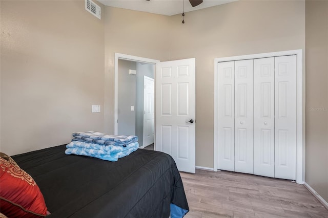 bedroom with a high ceiling, a closet, light wood-type flooring, and ceiling fan