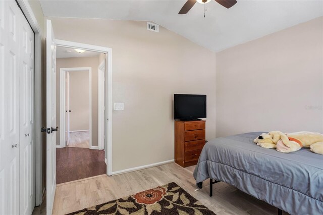 bedroom with light wood-type flooring, ceiling fan, vaulted ceiling, and a closet