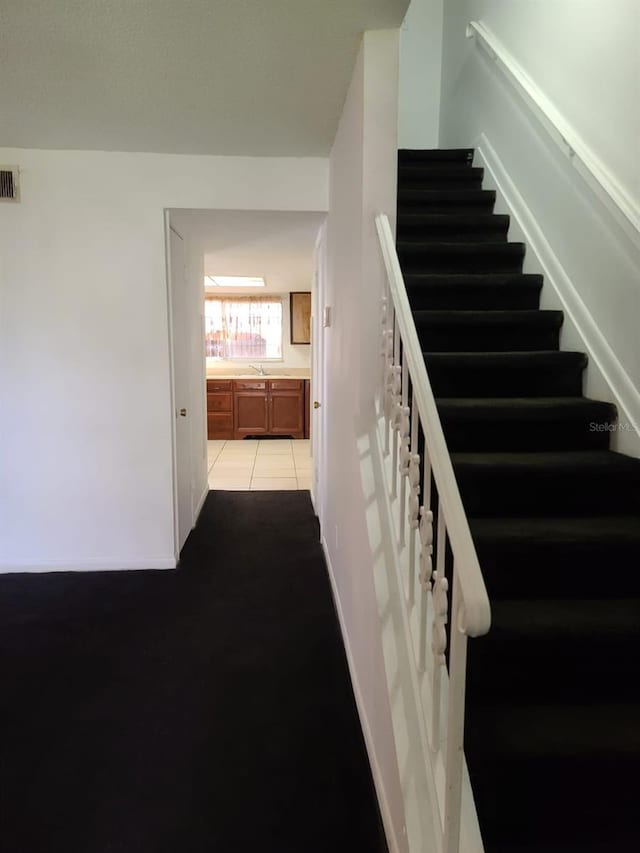 stairs featuring tile patterned floors and sink