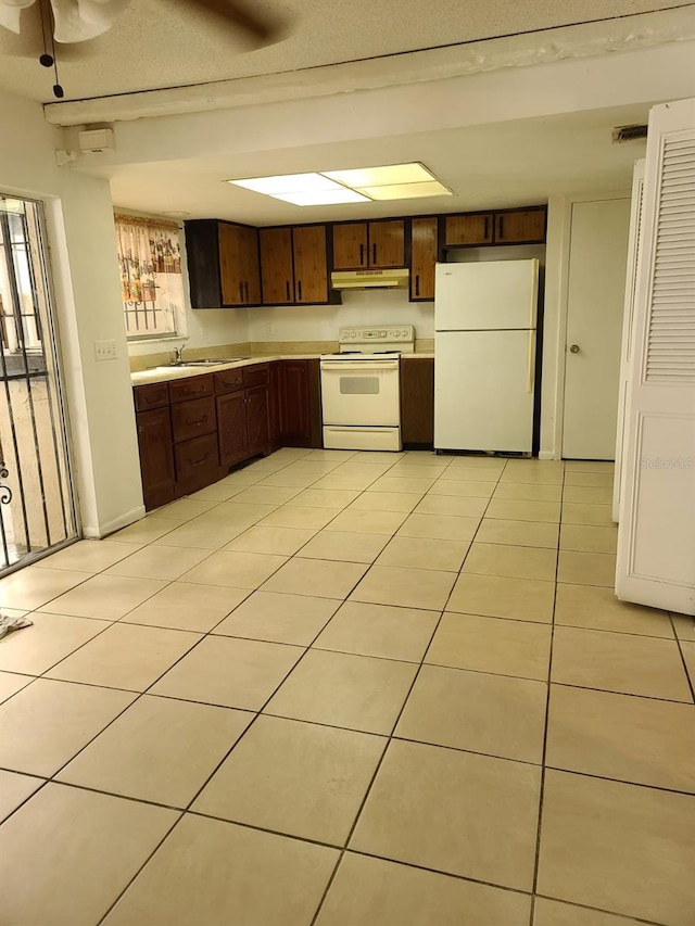 kitchen featuring white appliances, sink, ceiling fan, light tile patterned floors, and dark brown cabinetry