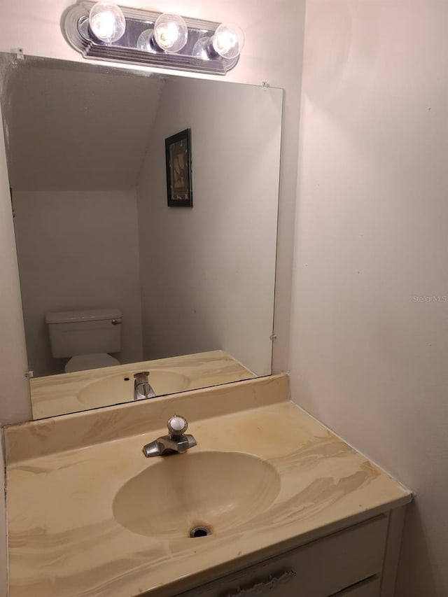 bathroom featuring vanity, vaulted ceiling, and toilet