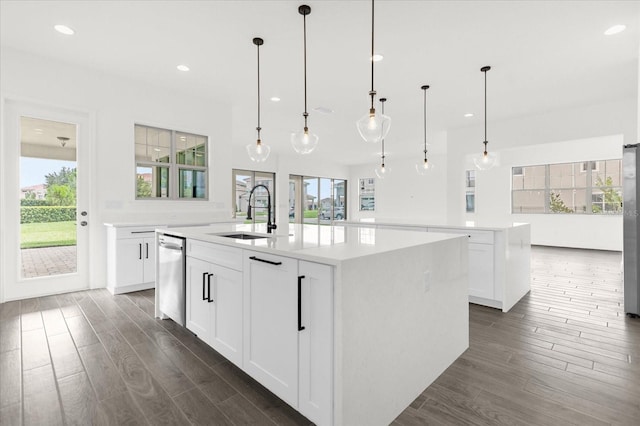 kitchen featuring white cabinets, pendant lighting, a center island with sink, and sink