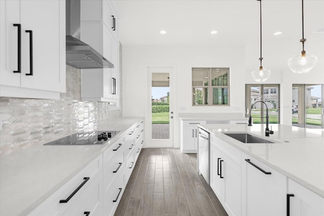 kitchen with wall chimney range hood, sink, pendant lighting, dishwasher, and white cabinetry