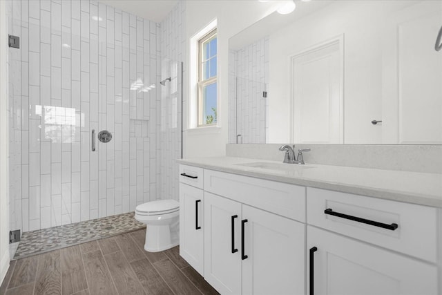 bathroom with toilet, vanity, and tiled shower