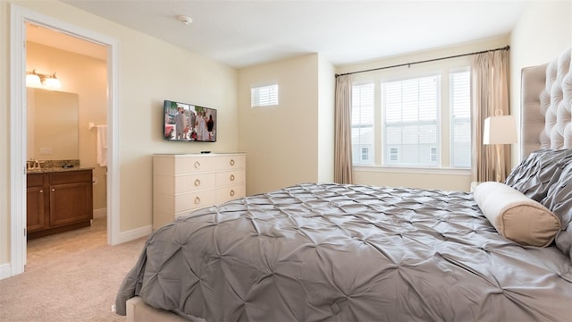 bedroom featuring light carpet and connected bathroom