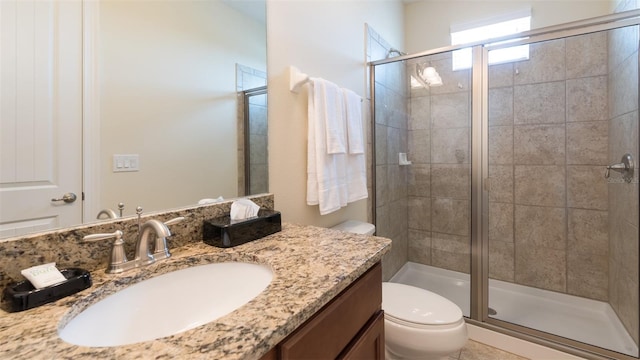 bathroom featuring a shower with shower door, vanity, and toilet