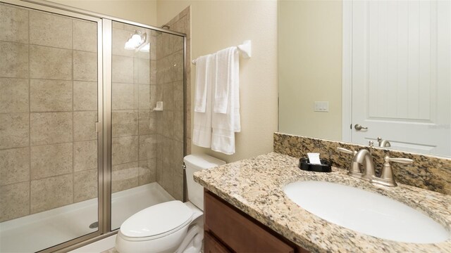 bathroom with vanity, a shower with door, and toilet