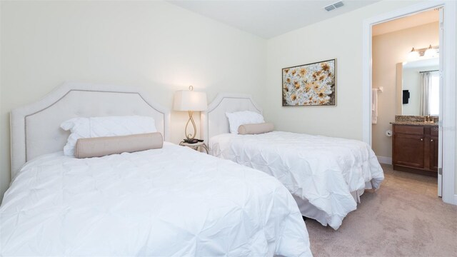 bedroom with sink, connected bathroom, and light colored carpet