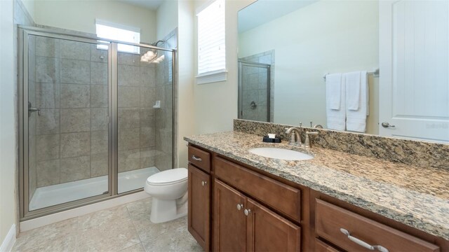 bathroom featuring tile patterned flooring, a shower with shower door, toilet, and vanity