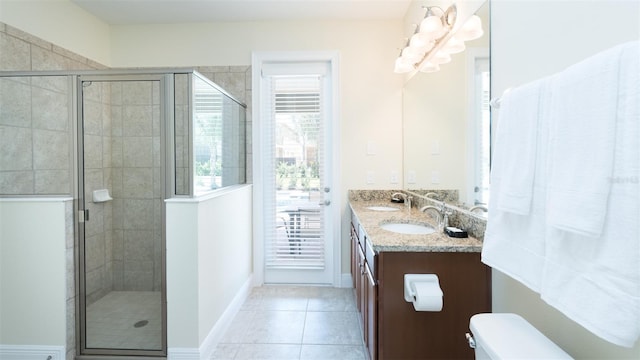 bathroom featuring tile patterned floors, double sink vanity, toilet, and a shower with door