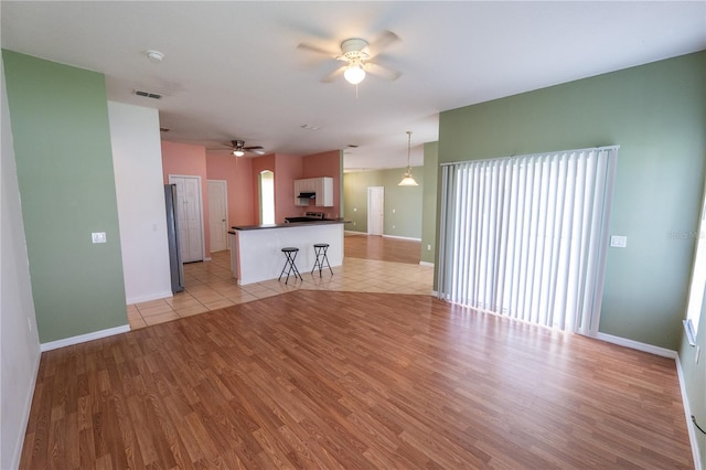 unfurnished living room with light hardwood / wood-style floors and ceiling fan