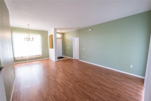 unfurnished living room featuring a chandelier and wood-type flooring