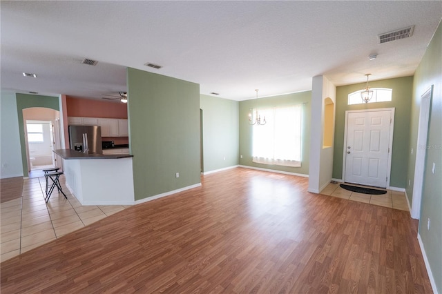 foyer featuring a textured ceiling, ceiling fan with notable chandelier, light hardwood / wood-style flooring, and a healthy amount of sunlight