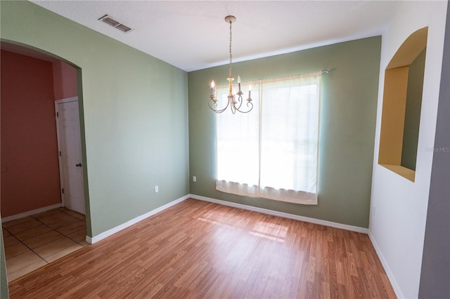 spare room featuring wood-type flooring and an inviting chandelier