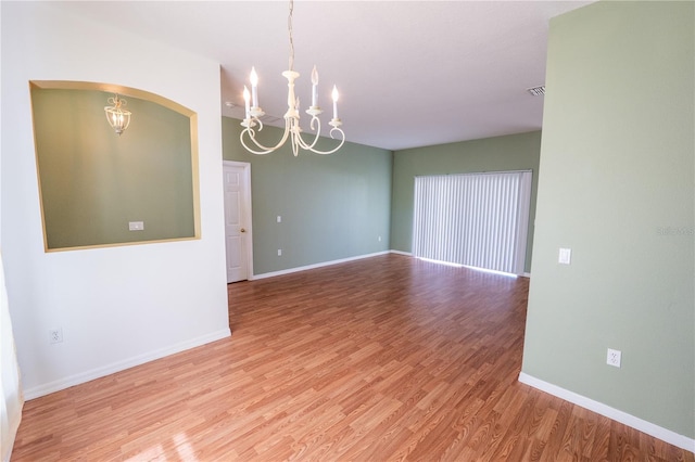 spare room featuring a notable chandelier and wood-type flooring