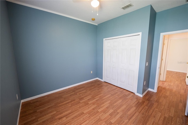 unfurnished bedroom featuring ceiling fan, wood-type flooring, and a closet