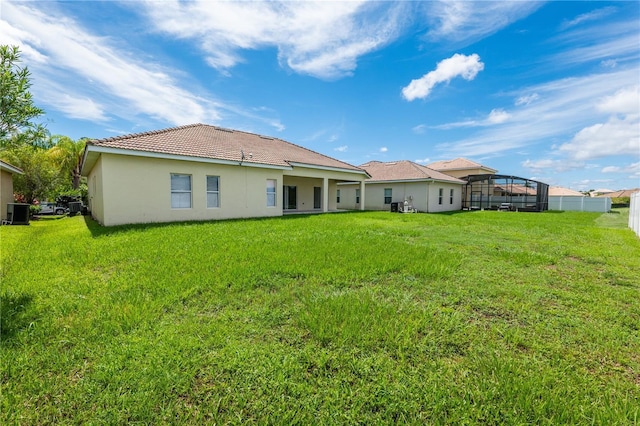 back of house featuring glass enclosure, a yard, and central AC unit