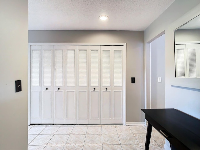 corridor with light tile patterned flooring and a textured ceiling