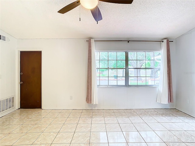 unfurnished room with ceiling fan, light tile patterned flooring, and a textured ceiling