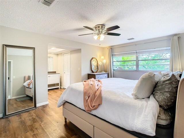 bedroom with ensuite bath, ceiling fan, hardwood / wood-style floors, a textured ceiling, and a closet