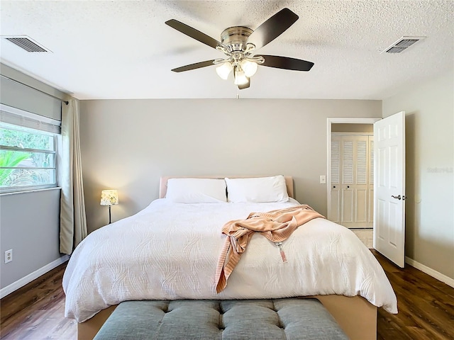 bedroom with ceiling fan, dark hardwood / wood-style floors, a textured ceiling, and a closet