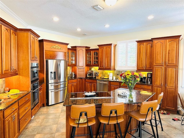 kitchen with brown cabinetry, appliances with stainless steel finishes, and a breakfast bar