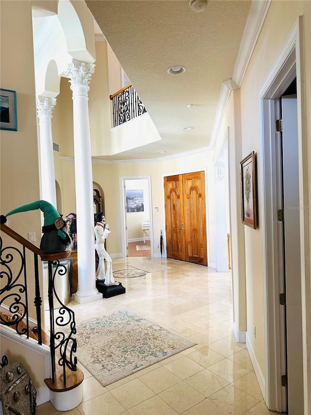 hallway with baseboards, decorative columns, arched walkways, ornamental molding, and a textured ceiling