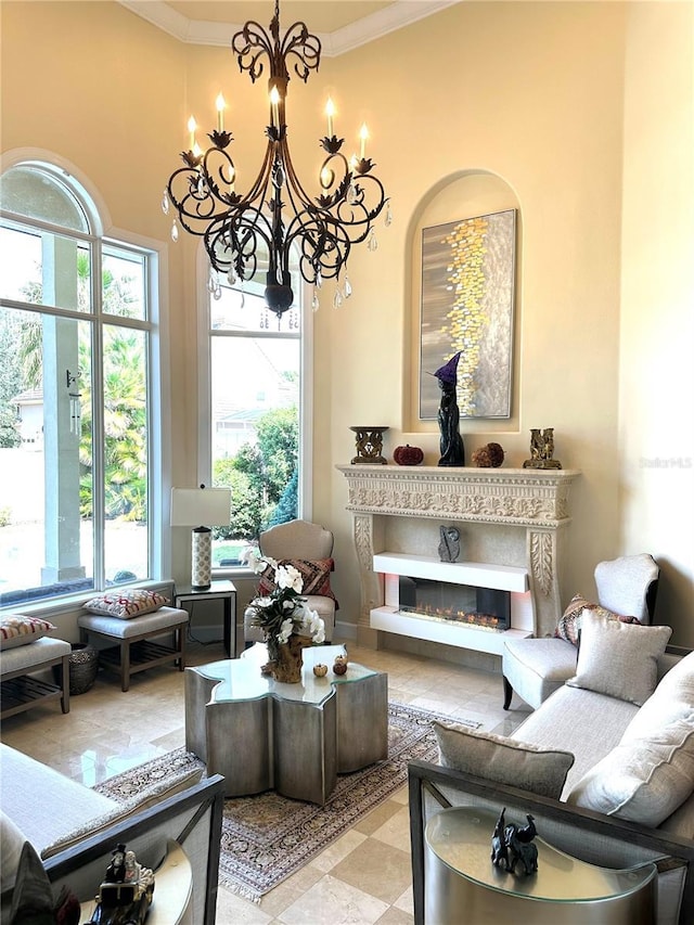 living room featuring a chandelier, a glass covered fireplace, and ornamental molding