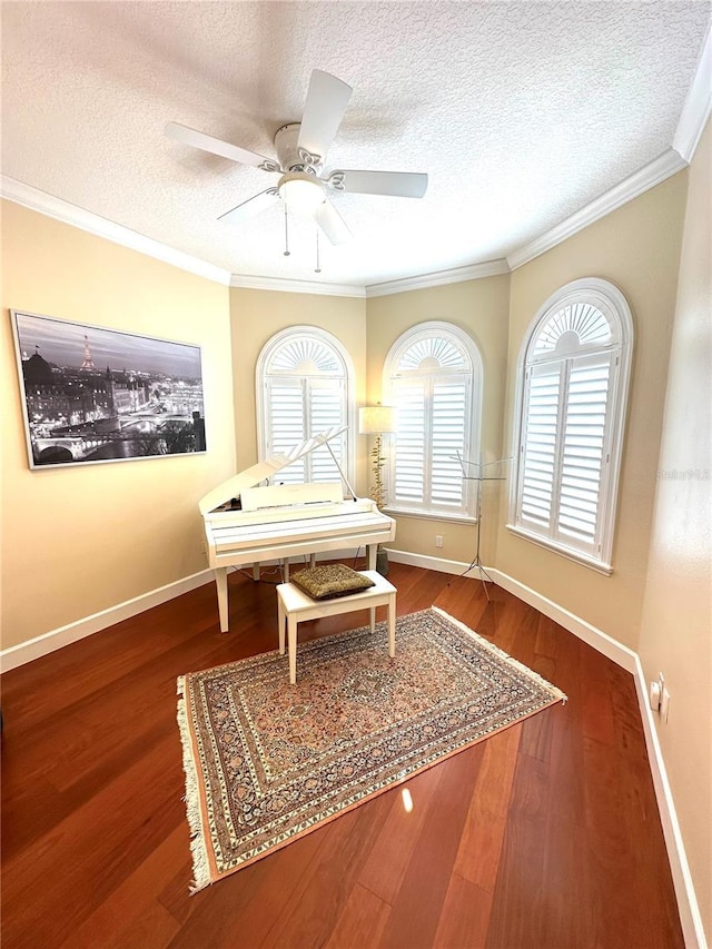 interior space with baseboards, a textured ceiling, wood finished floors, and ornamental molding