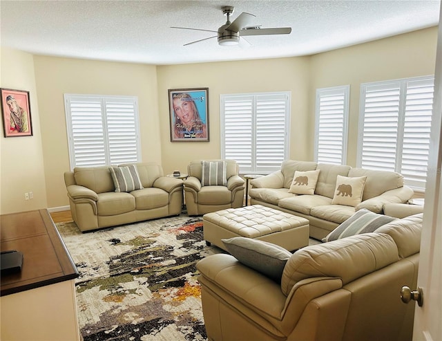 living area featuring a ceiling fan and a textured ceiling