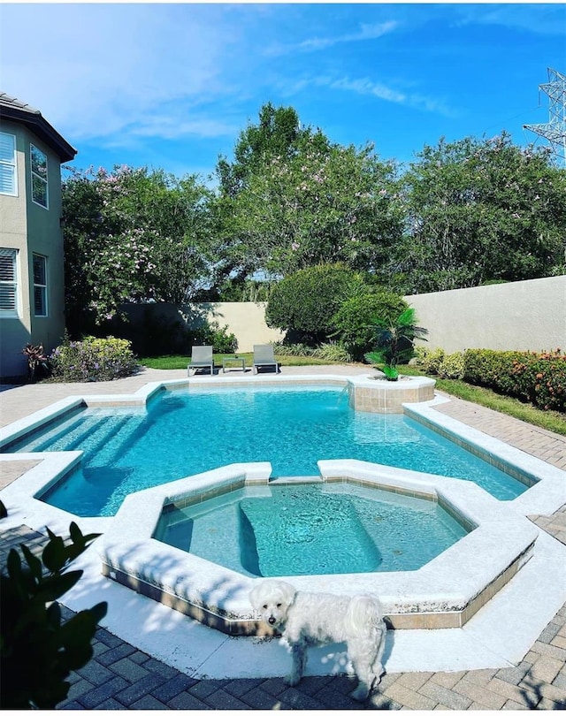 view of pool with a fenced backyard and a pool with connected hot tub